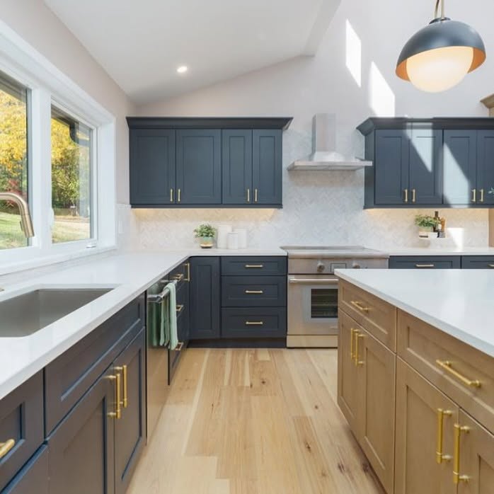 Deep blue kitchen cabinetry with a natural wood island and brass hardware